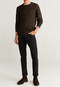 Brauner strukturierter Strickpullover mit gerippten Bündchen und Saum, kombiniert mit schwarzen Hosen und dunkelbraunen Ankle Boots.