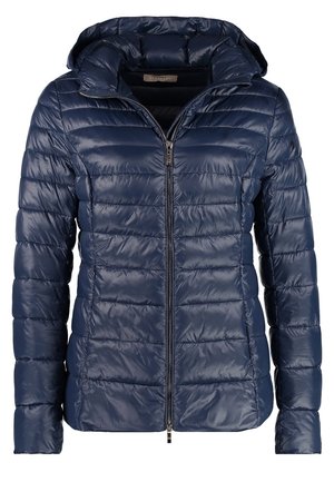 Navy puffer jacket with a hood, paired with a white graphic T-shirt featuring colorful floral design, distressed blue jeans, and tan ankle boots.