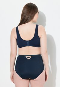 Námořnická modrá dvoudílná plavky s hladkým materiálem, širokými ramínky, háčkovým zapínáním na zádech a křížovým detailem na vysokých spodních kalhotkách.
