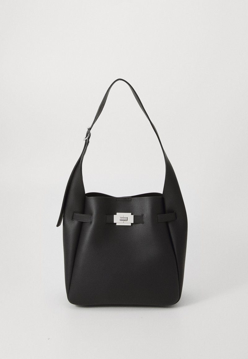 Sac à épaule en cuir noir avec une forme incurvée, présentant un accent en métal argenté et des sangles plates. Texture lisse avec un minimum de détails.