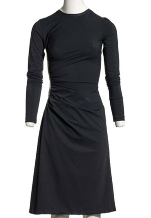Robe noire à manches longues longue jusqu'aux genoux avec un col rond et de légers fronces sur le côté, présentée sur un mannequin blanc.