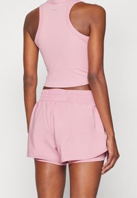 Różowy sportowy crop top i szorty wykonane z miękkiego materiału o luźnym kroju, z elastycznym paskiem w talii i minimalnym logo.