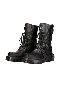 Bottes en cuir noir avec tige haute, devant lacé et plusieurs accents de boucles. Semelle en caoutchouc épaisse avec quincaillerie détaillée et texture.