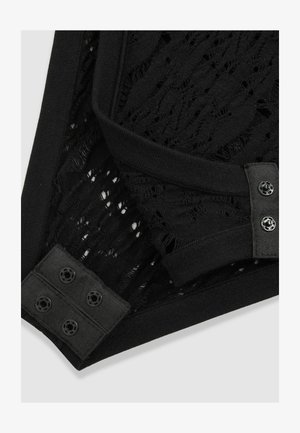 Prenda de punto negra con patrón de encaje texturizado, que presenta una cinturilla suave y acentos de botones para el cierre.