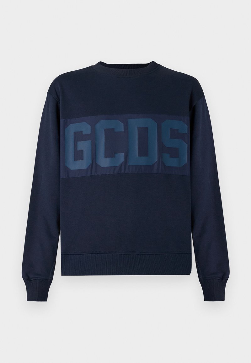 Tumši zilas krāsas sporta krekls ar apaļu dekoltē un garām piedurknēm. Uzkrītošs tumši zils "GCDS" logo uz krūšu daļas. Audums no kokvilnas maisījuma.