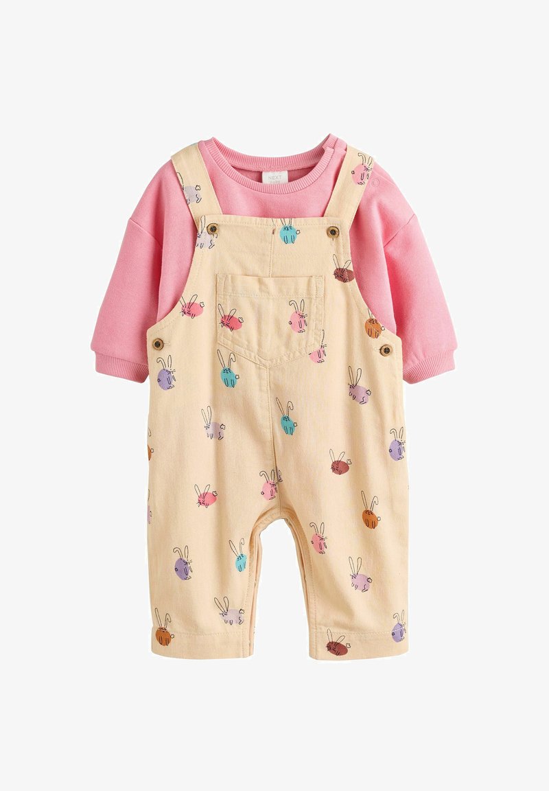 Sweatshirt rose clair associé à des salopettes jaunes avec un motif de lapins de différentes couleurs ; tissu doux, bretelles ajustables, poches avant.