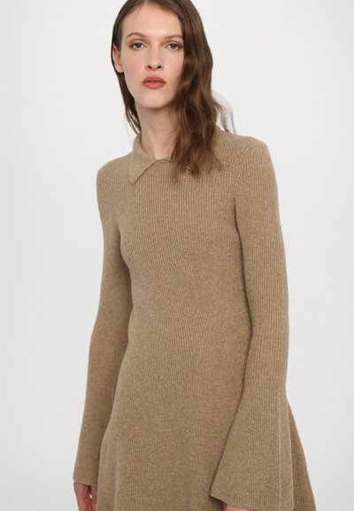 Rochie tricotată cu model în relief, de culoare bej, cu guler și mâneci amplu, confecționată dintr-un material moale și texturat.