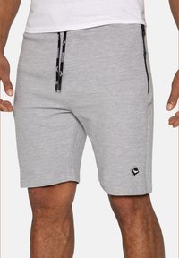 Grå svedshorts lavet af ribbet stof. Har en sort lynlås-lomme og kontrastfarvet snor med branding. Slim fit, knælangt design.