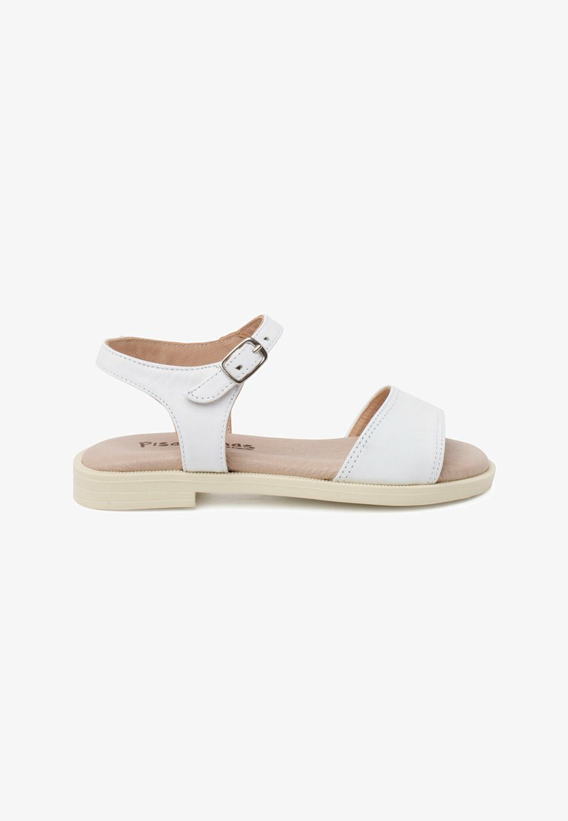 White sandal with a flat sole, adjustable ankle strap, and open toe. Features stitched detailing and a smooth leather-like texture.