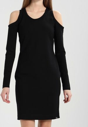 Robe noire à épaules dénudées en tissu doux. Forme ajustée avec des manches longues, décolleté arrondi et accents subtils au niveau de l'ourlet.