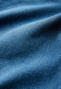 Tamsiai mėlyno džinsinio audinio, turinčio subtilią tekstūrą su matomais audimo raštais ir lygiu paviršiumi, krentančio su minkštais raukšlėmis.