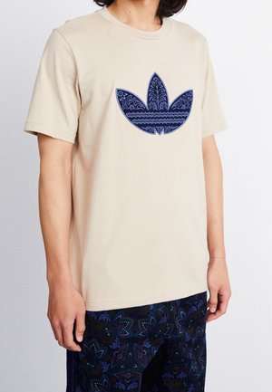 Béžové bavlněné tričko se námorně modrou grafikou třílistého vzoru s jemnými ornamenty. Krátké rukávy a kulatý výstřih.