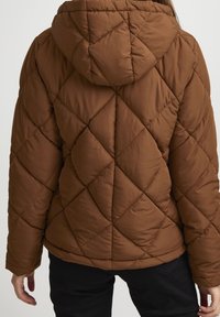Veste matelassée marron avec capuche, présentant un motif géométrique en losanges et une texture lisse. Coutures visibles et taille cintrée.