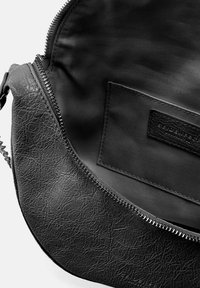 Interior de bolso de cuero sintético negro con un acabado texturizado, cierre con cremallera y un forro de tela con un bolsillo parche discreto.