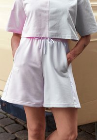 Lättviktsbomullstopp i ljusgrå, tillsammans med sweatshorts med en gradient från ljuslila till vit, med sidofickor.