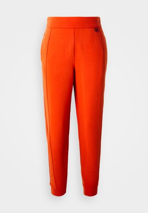 Lyse oransje tapered joggebukser med elastisk liv, sidelommer og ribbede mansjetter, vist frontvendt på en hvit bakgrunn.