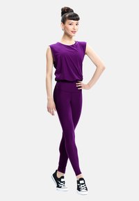 Purple activewear set featuring a sleeveless top and high-waisted leggings, made from smooth fabric. Paired with black sneakers.
