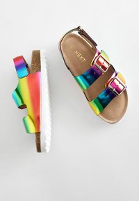 Regnbågsmetalliska sandaler med två justerbara spännen, mjuk brun innersula och vit gummisula. Slät yta och livfulla färgövergångar.