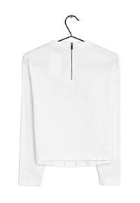 Haut blanc à manches longues présenté sur un cintre. Comprend un col rond et un détail de fermeture éclair au dos. Le tissu semble lisse et léger.