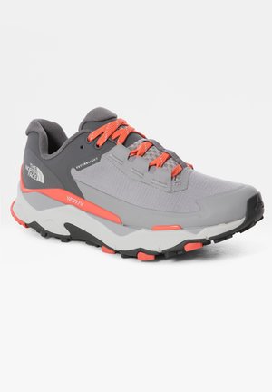 Chaussure de trail running grise et corail avec semelle texturée, tige en mesh, col rembourré et logo « The North Face » sur le côté.