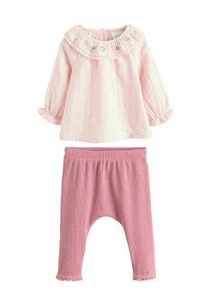 Maglia a maniche lunghe rosa chiaro con ricamo floreale sul colletto; abbinata a pantaloni harem rosa a coste con orlo arricciato.