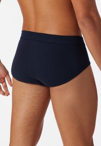 Slips da bagno blu navy realizzati in tessuto morbido, con una vestibilità a vita bassa, elastico in vita e design minimalista.