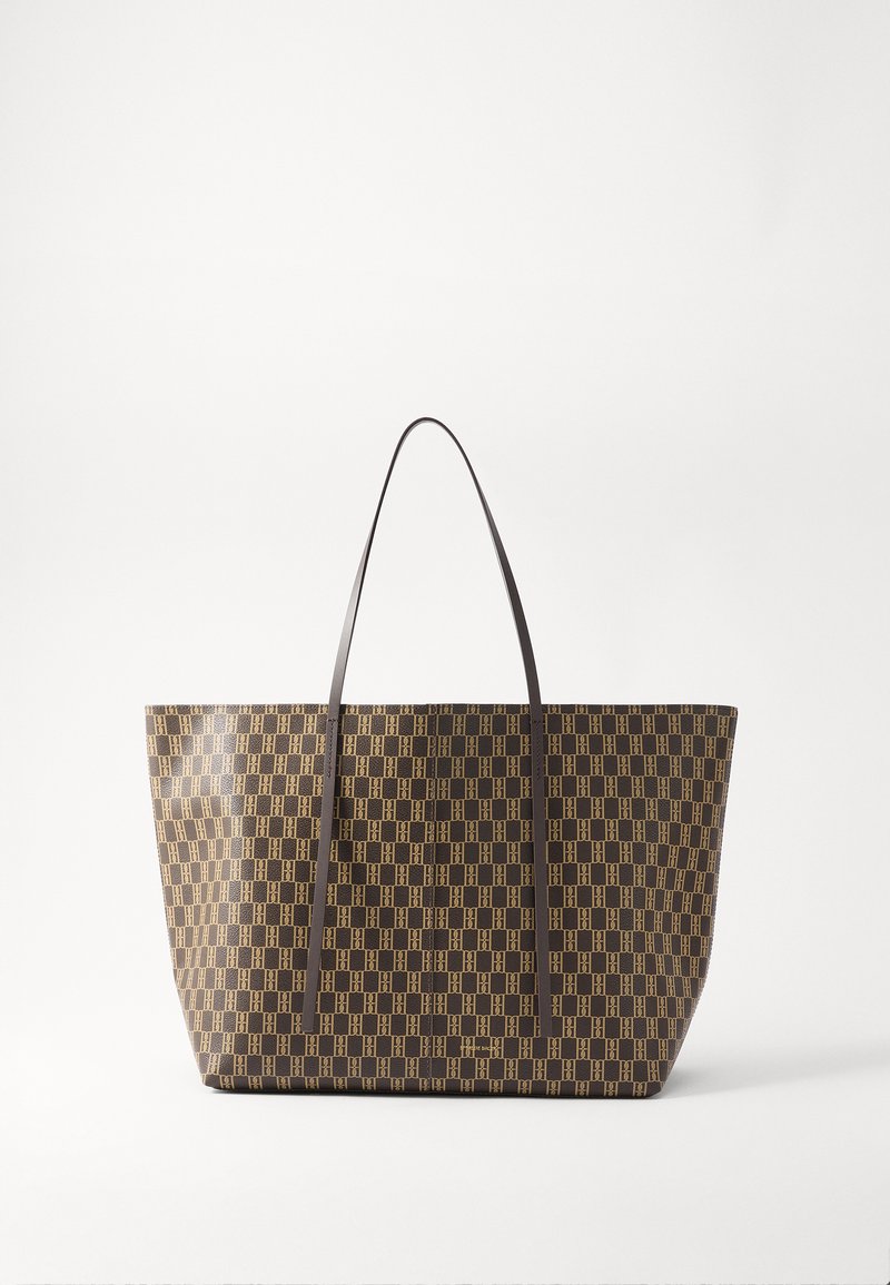 Tasche aus braunem, gemustertem Material mit hellgoldenen geometrischen Designs. Sie hat zwei dunkle Lederhenkel und eine offene Oberseite.