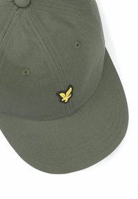 Groene katoenen pet met een afgeronde kroon, een gebogen klep en zwarte stikselaccenten. Voorzien van een klein geel geborduurd logo van een vogel.