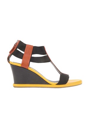 Sandale à talon compensé avec lanières noires, accent texturé marron, semelle jaune et fermeture éclair à l'arrière sur fond blanc.