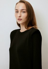 Mustat hupparit, joissa on pyöreä kaula-aukko, pitkät hihat ja sileä pinta. Yksinkertainen muotoilu, ei näkyviä kuvioita tai yksityiskohtia.
