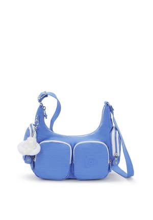 Blue fabric shoulder bag with two front pockets, white accents, adjustable strap, and fluffy white keychain charm attached.