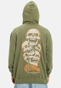 Felpa verde oliva con grafica sul retro di tre teschi in bianco e nero con occhi arancioni, con polsini e orlo a coste.