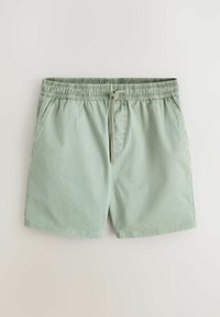 Shorts décontractés vert clair avec ceinture élastique, cordon de serrage et poches latérales sur fond clair.
