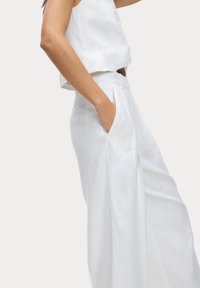 Witte linnen broek met brede pijpen en een gladde textuur, voorzien van zijzakken en een op maat gemaakte tailleband. Eenvoudig en strak ontwerp.