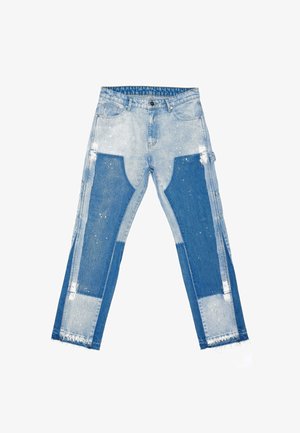 Világoskék farmernadrág sötétebb kék foltokkal az elülső lábakon, fehér festékfröccsenésekkel, gombos záródással és nyers, bolyhos szegélyekkel.