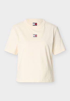 Tricou din bumbac de culoare crem, cu mâneci scurte și decolteu rotund. Prezintă un logo mic, colorat „TOMMY JEANS” pe piept.