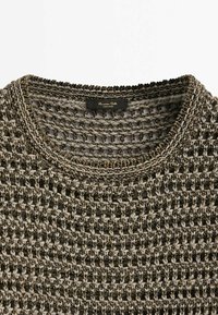 Chunky knit sweater in black and grey tones. Features a circular neckline and open weave texture. Label visible inside collar.