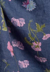 Blumenstoff mit einem dunkelblauen Hintergrund sowie rosa und grünen Blütenmustern. Die Textur wirkt weich und gewebt, mit aufwendigen Details.