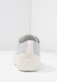 Šedá semišová bota s bílou gumovou podrážkou. Zadní část má kontrastní bílou patu a minimální švy.