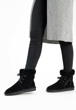 Botas negras hasta el tobillo, hechas de suave ante, con un puño de piel sintética, cordones en la parte frontal y una cremallera lateral para un acceso fácil. Suela de goma plana.