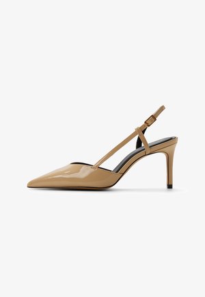 Beige lakleren pumps met hoge hak en open hiel, voorzien van een spitse neus en een dunne verstelbare band met gouden gesp.