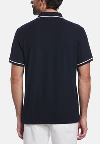 Marineblauwe polo met een eenvoudig ontwerp, korte mouwen en witte accenten op de mouwuiteinden en kraag. Zachte, gladde stoftextuur.