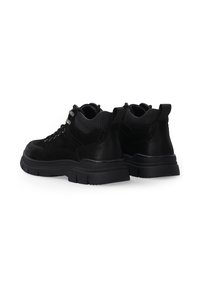 Schwarze Wanderschuhe aus einer Kombination von strukturiertem Wildleder und glattem Leder, mit einer dicke Gummisohle und Metallösen für die Schnürsenkel.