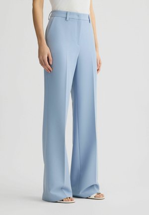 Light blue wide-leg trousers with pleats, made from smooth fabric, featuring a belted waist and side pockets, paired with open-toe sandals.