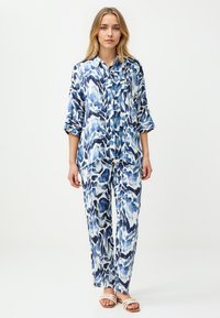 Lässiges Set aus blau-weißem Muster mit Shirt und Hose, hergestellt aus leichtem Stoff. Das Shirt hat einen Kragen und hochgekrempelte Ärmel.