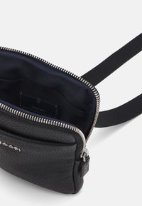 Black leather crossbody bag with textured exterior, silver zipper, and fabric lining. Interior contains a card pocket. Adjustable strap included.