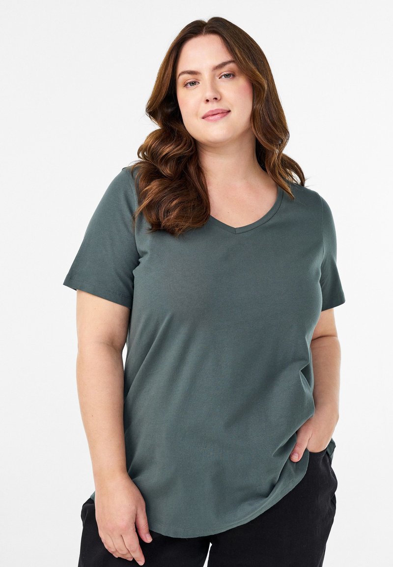 Zelené tričko s krátkým rukávem a véčkovým výstřihem, vyrobené z měkké tkaniny, s volným střihem a zaobleným lemem pro pohodlí a snadné nošení.