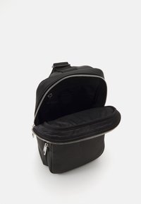 Sac à dos noir en matériau texturé, doté d'une ouverture zippée, d'un intérieur spacieux et d'une poche à l'intérieur pour une meilleure organisation.