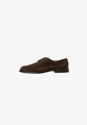 Zapato oxford de ante marrón con punta redonda, cinco ojetes para los cordones y una suela de cuero delgada. Textura suave y diseño minimalista.
