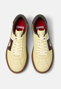 Gula lädersneakers med brun sidopanel, vita detaljer och bruna gummisulor. Snören och röd innerfoder fulländar designen.